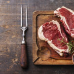 Raw fresh meat Ribeye Steak, seasoning and meat fork on dark bac