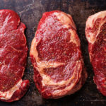 Three cuts of Raw fresh meat Steaks and seasonings on dark backg